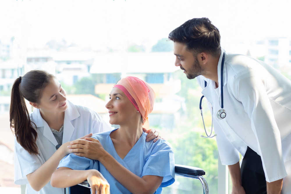 Woman speaking with doctors. Image credit: Nutnutchar NAV via Shutterstock.