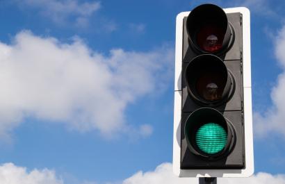 A green traffic light against a blue sky with a few fluffy white clouds. Image by Eddie J. Rodriquez via Shutterstock.