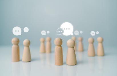 Little wooden figurines talking to each other, representing networking. Image by THEBILLJR via Shutterstock.