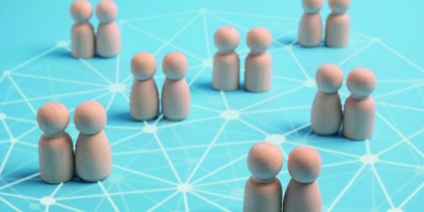 Pairs of wooden figures on a network pattern. Image via Shutterstock