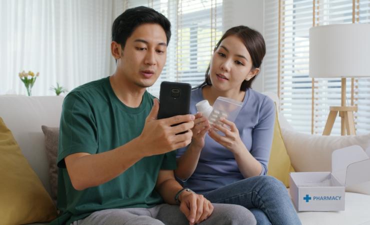 A young couple consult the apps to find out information about their medication. Image by Chay_Tee via Shutterstock.