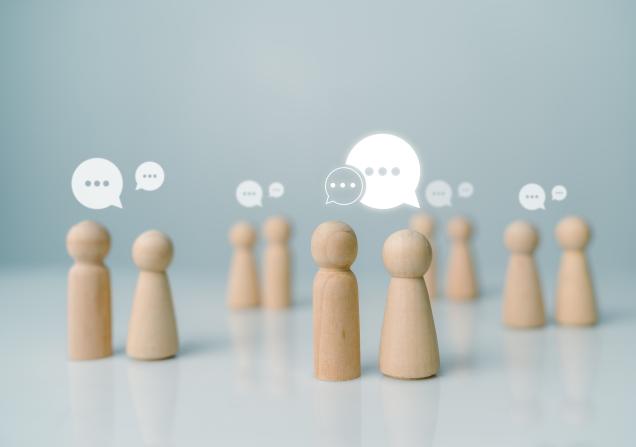 Little wooden figurines talking to each other, representing networking. Image by THEBILLJR via Shutterstock.