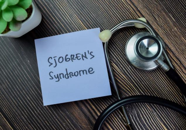 Sjögren’s syndrome written on a small piece of paper on a desk next to a stethoscope. Image credit: bangoland via Shutterstock.