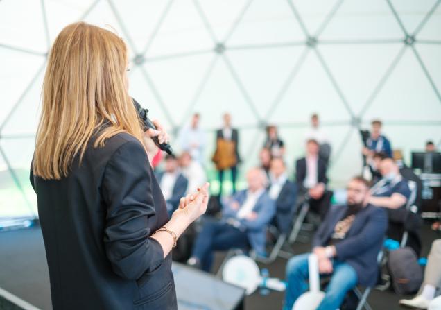 Woman pitching idea to room. Image by Anton Gvozdikov via Shutterstock.