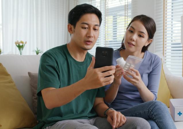 A young couple consults the apps to find out information about their medication. Image by Chay_Tee via Shutterstock.