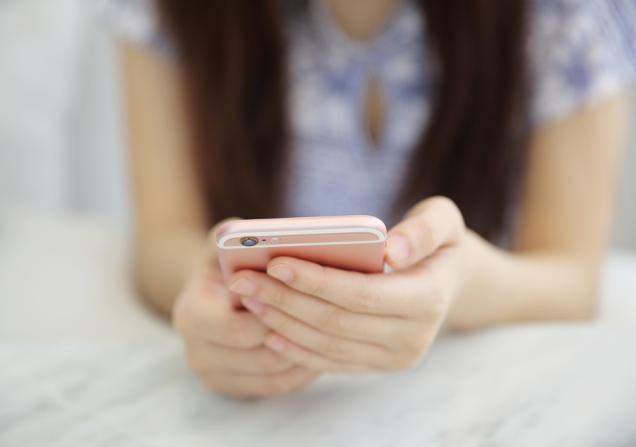 Close up of the hands of a woman holding a smartphone. Image by Piyato via Shutterstock