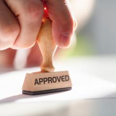 Image by Brian A Jackson via Shutterstock. A hand stamping something with an 'APPROVED' stamp.