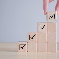 Image by Tanoy1412 via Shutterstock. A set of wooden blocks, rising in height, with a tick at the top of each column to show regulatory approval of health research results.